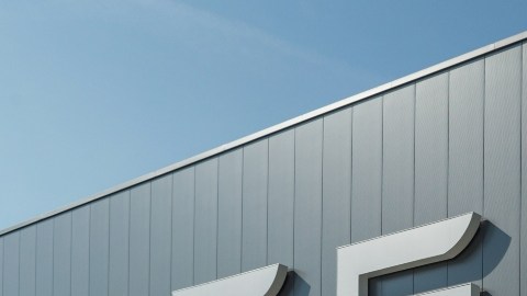 Imagen de varios vehículos de la marca Telsa, estacionados frente a un hangar con las letras de la marca colocadas en uno de los muros.