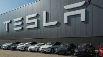 Imagen de varios vehículos de la marca Telsa, estacionados frente a un hangar con las letras de la marca colocadas en uno de los muros.