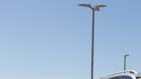 Imagen de una camioneta de la marca Volkswagen de color plata, estacionada en medio de un patio con otros vehículos.