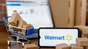 Imagen de varias cajas en miniatura, un carrito de compra en miniatura, un teléfono celular en el que se ve el logotipo de Walmart y una computadora portátil.
