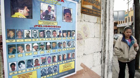 Una mujer camina junto a un cartel que ofrece recompensas de hasta cinco millones de dolares, por informacion que conduzca a la detención de miembros del Cártel de Sinaloa. / Foto: AFP/Getty Images