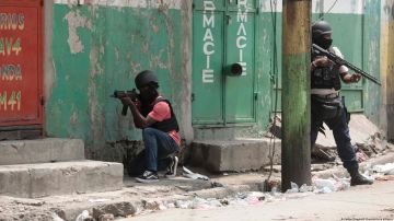 Agentes de policía se ponen a cubierto durante una operación antipandillas en el barrio de Portail de Puerto Príncipe.