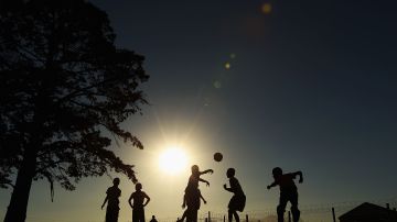 GEORGE, SOUTH AFRICA - JUNE 25: Children play football as they wait for the arrival of the Japan football team at the Lawaaikamp Sport ground for township visit during the FIFA 2010 World Cup on June 25, 2010 in George, South Africa. (Photo by Mark Kolbe/Getty Images)