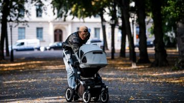 A man walks his baby in a baby stroller at Humlegarden in Stockholm on September 24, 2020. - While France has just increased paternity leave to 28 days, in Sweden, a pioneer in gender equality, parents share 480 days off, which can be taken until the child's 12th birthday at 80% of the salary for the first 390 days and fathers have a minimum of three months, but only half of them take full advantage of it. (Photo by Jonathan NACKSTRAND / AFP) (Photo by JONATHAN NACKSTRAND/AFP via Getty Images)