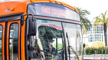 A man wearing a face mask drives a bus with a sign in the downtown area on March 8, 2021 in Los Angeles, California. (Photo by VALERIE MACON / AFP) (Photo by VALERIE MACON/AFP via Getty Images)