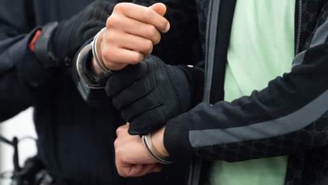 A judical officer brings a handcuffed defendant into the courtroom in Dresden, eastern Germany, on March 29, 2022, for the continuation of the trial over a jewellery heist on the Green Vault (Gruenes Gewoelbe) museum in Dresden's Royal Palace in November 2019. - Six members of a notorious criminal gang are on trial in Germany over the spectacular heist in which 18th-century jewels were snatched from the state museum in Dresden. They are accused of gang robbery and arson after the brazen night raid on The Green Vault museum on November 25, 2019. (Photo by Sebastian Kahnert / POOL / AFP) (Photo by SEBASTIAN KAHNERT/POOL/AFP via Getty Images)