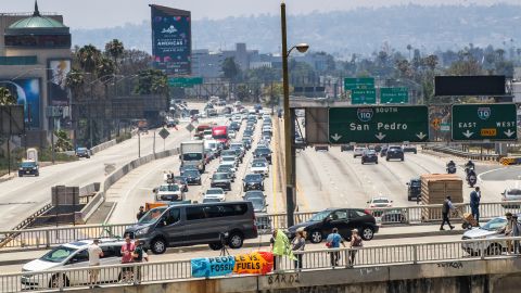 People hold a sign protesting against fossil fuels over the 110 Freeway during the 9th Summit of the Americas near the Los Angeles Convention Center in Los Angeles, California, on June 8, 2022. (Photo by Apu GOMES / AFP) (Photo by APU GOMES/AFP via Getty Images)