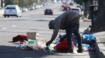 An unnamed person rummages through trash along Sunset Boulevard in Los Angeles, California, December 19, 2022. - A state of emergency over spiraling levels of homelessness was declared in Los Angeles on Monday as the new mayor pledged a "seismic shift" for one of the most intractable problems in America's second biggest city. Tens of thousands of people sleep rough on Los Angeles streets every night, in an epidemic that shocks many visitors to one of the wealthiest urban areas on the planet. (Photo by DAVID SWANSON / AFP) (Photo by DAVID SWANSON/AFP via Getty Images)