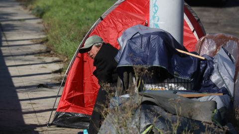 An unhoused person sits next to their tent along Glendale Boulevard in Los Angeles, California, December 19, 2022. - A state of emergency over spiraling levels of homelessness was declared in Los Angeles on Monday as the new mayor pledged a "seismic shift" for one of the most intractable problems in America's second biggest city. Tens of thousands of people sleep rough on Los Angeles streets every night, in an epidemic that shocks many visitors to one of the wealthiest urban areas on the planet. (Photo by DAVID SWANSON / AFP) (Photo by DAVID SWANSON/AFP via Getty Images)