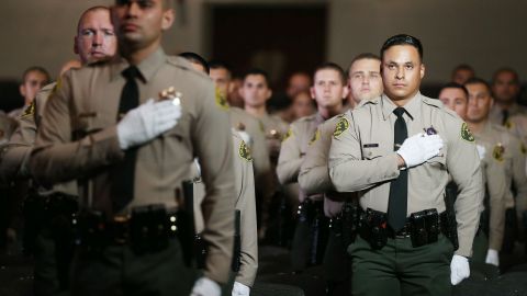 MONTEREY PARK, CALIFORNIA - AUGUST 21: Graduates of Los Angeles County Sheriff's Department Academy Class 451 stand for the pledge of allegiance at their graduation ceremony at East Los Angeles College amid the COVID-19 pandemic on August 21, 2020 in Monterey Park, California. Graduates were seated with social distancing and family members were not allowed inside the ceremony due to restrictions in place to prevent the spread of the coronavirus. (Photo by Mario Tama/Getty Images)