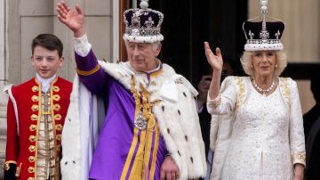 El rey Carlos III y la reina Camila saludan desde el balcón del Palacio de Buckingham.