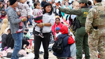Una agente de CBP habla a inmigrantes transportados desde un campamento entre muros fronterizos, entre San Diego y Tijuana.