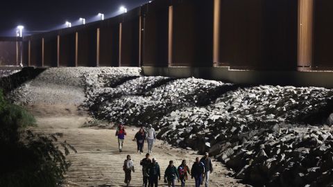 YUMA, ARIZONA - MAY 11: Immigrants seeking asylum in the United States walk along the border fence on their way to be processed by U.S. Border Patrol agents in the early morning hours after crossing into Arizona from Mexico on May 11, 2023 in Yuma, Arizona. A surge of immigrants is expected with today's end of the U.S. government's Covid-era Title 42 policy, which for the past three years has allowed for the quick expulsion of irregular migrants entering the country. Over 29,000 immigrants are currently in the custody of U.S. Customs and Border Protection ahead of the sunset of the policy tonight. (Photo by Mario Tama/Getty Images)