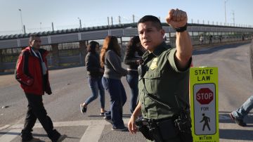 Un agente de CBP detiene el tráfico mientras los inmigrantes son deportados por un puente internacional a México, en esta foto de archivo.