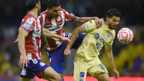 Henry Martín disputando un balón contra jugadores del Atlético San Luis.