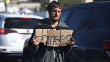 An unhoused person holds a sign reading "Homeless" as they solicits for money in traffic on Glendale boulevard in Los Angeles, California, December 19, 2022. - A state of emergency over spiraling levels of homelessness was declared in Los Angeles on Monday as the new mayor pledged a "seismic shift" for one of the most intractable problems in America's second biggest city. Tens of thousands of people sleep rough on Los Angeles streets every night, in an epidemic that shocks many visitors to one of the wealthiest urban areas on the planet. (Photo by DAVID SWANSON / AFP) (Photo by DAVID SWANSON/AFP via Getty Images)
