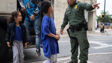 Un agente de la Patrulla Fronteriza observa a niños y familias migrantes que llegan a un centro de procesamiento en Brownsville, Texas.