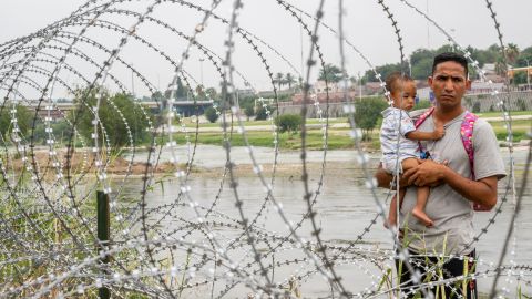 Una familia de inmigrantes que busca asilo mira a través de una cerca el 14 de junio de 2023 en Eagle Pass, Texas.