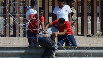 Inmigrantes cruzando las alambradas en el muro fronterizo entre Ciudad Juárez y El Paso.