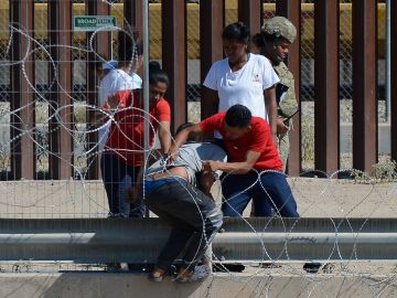 Inmigrantes cruzando las alambradas en el muro fronterizo entre Ciudad Juárez y El Paso.