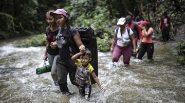 Migrantes cruzan un río mientras cruzan el Tapón del Darién de Colombia a Panamá,