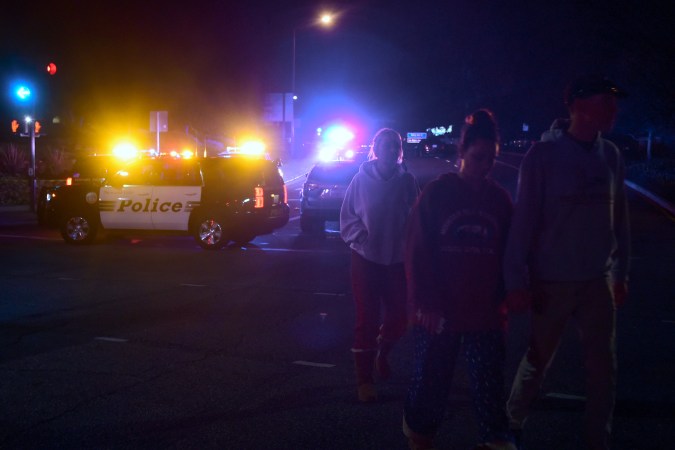 People walk away from the scene as it unfurls at the intersection of US 101 freeway and the Moorpark Rad exit as police vehicles close off the area responding to a shooting at a bar in Thousand Oaks, California on November 8, 2018. - Twelve people, including a police sergeant, were shot dead in a shooting at a night club close to Los Angeles, police said Thursday. All the victims were killed inside the bar in the suburb of Thousand Oaks late on Wednesday, including the officer who had been called to the scene, Sheriff Geoff Dean told reporters. The gunman was also dead at the scene, Dean added. The bar was hosting a college country music night. (Photo by Frederic J. BROWN / AFP) (Photo credit should read FREDERIC J. BROWN/AFP via Getty Images)