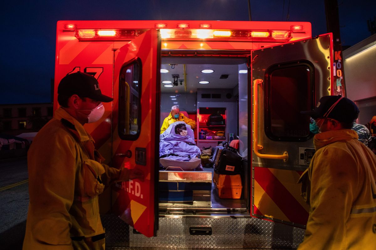 TOPSHOT - Paramedics of the LAFD Station No9 wear a face mask as a preventive measure against the spread of the COVID-19 novel coronavirus from a homeless woman who had seizures on the street at Skid Row, before boarding her in the ambulance to go to a hospital on April 12, 2020 in downtown Los Angeles, California.  - One of the busiest fire station in the country, LA Fire Station 9 is on the front lines of California's homeless crisis and Coronavirus pandemic.  (Photo by Apu GOMES / AFP) (Photo by APU GOMES/AFP via Getty Images)