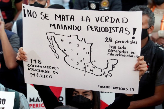 Un periodista sostiene un cartel que dice:"matando periodistas no se mata la verdad" durante una protesta.