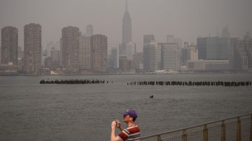 Un hombre fotografía Nueva York con el intenso smog traído por el humo de los incendios forestales de Canadá.