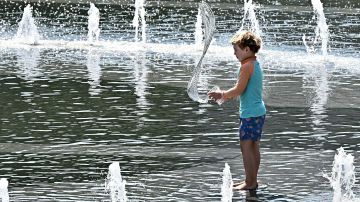 A child tosses water from a cup while playing in the water fountain at Grand Park in Los Angeles, California, on July 2, 2023. After months of unseasonable weather across Southern California, a heatwave has arrived in time for the July 4th holiday, bringing triple digit temperatures. (Photo by Frederic J. BROWN / AFP) (Photo by FREDERIC J. BROWN/AFP via Getty Images)