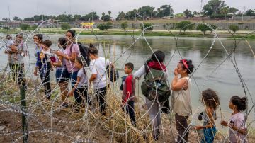 Personas que buscan asilo hablan con agentes de la ley después de cruzar ilegalmente el Río Grande en Texas.