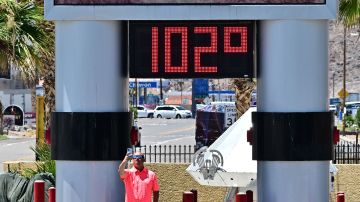 A man takes a selfie beside a thermometer showing 102 degrees farenheit in Baker, California on July 11, 2023, amidst a heat wave. More than 50 million Americans are set to bake under dangerously high temperatures this week, from California to Texas to Florida, as a heat wave builds across the southern United States. (Photo by Frederic J. BROWN / AFP) (Photo by FREDERIC J. BROWN/AFP via Getty Images)