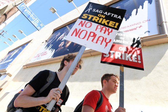 Members of the Writers Guild of America and the Screen Actors Guild walk a picket line outside Paramount Studios in Los Angeles, California, on July 14, 2023. Tens of thousands of Hollywood actors went on strike at midnight July 13, 2023, effectively bringing the giant movie and television business to a halt as they join writers in the first industry-wide walkout for 63 years. (Photo by VALERIE MACON / AFP) (Photo by VALERIE MACON/AFP via Getty Images)