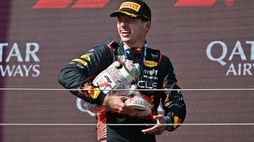 Max Verstappen sonríe con su trofeo partido en dos.