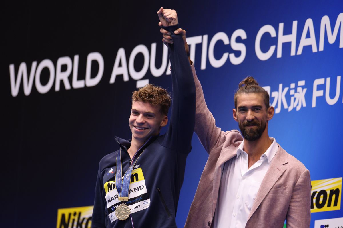 Michael Phelps levanta el brazo del hombre que batió el último récord mundial que tenía vigente.