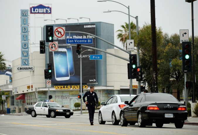 LOS ANGELES, CA - JUNE 25: Los Angeles Police Department officers search cars during a massive manhunt for a suspect who attempted to kill two detectives on June 25, 2013 in Los Angeles, California. The shooting happened in the early morning hours as the two detectives were ambushed and slightly injured outside the Los Angeles Police Department's Wilshire Station, prompting the closure of a 25-square-block area in the Mid-City section of Los Angeles. (Photo by Kevork Djansezian/Getty Images)