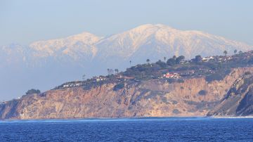 The snow-capped peaks of the San Gabriel Mountains can be seen in the distance from the affluent community of Rancho Palos Verdes on January 12, 2016, where cliffs hug the coastline with hilltop homes offering ocean views of the Pacific Ocean, south of Los Angeles. AFP PHOTO/FREDERIC J. BROWN / AFP / FREDERIC J BROWN (Photo credit should read FREDERIC J BROWN/AFP via Getty Images)