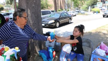Bertha Castillo, vendedora, entrega un raspado a una de las pequeñas en el parque.