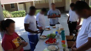Los seis migrantes liberados del Centro de Detención de Adelanto se unen en oración para bendecir los alimentos.