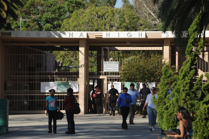 People gather at the entrance to Gardena High School in Gardena, California January 18, 2011 after two students were shot, one in the head, when a gun went off accidentally in a classroom. A student suspect was detained after police reinforcements were rushed to the high school south of central Los Angeles, where the campus was locked down after the mid-morning incident. AFP PHOTO / ROBYN BECK (Photo credit should read ROBYN BECK/AFP via Getty Images)