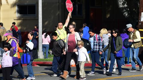 An Alhambra Unified School District crossing guard stops traffic for parents picking up their children from Ramona Elementary School on February 4, 2020 in Alhambra, California. - As the coronavirus outbreak spreads, fuelling rumors and misinformation, a petition to cancel all classes in one US school district for fear of the virus has garnered nearly 14,000 signatures. The online petition posted on Change.org urges the Alhambra Unified School District located east of Los Angeles and with a heavily Asian population, to basically shut down until the outbreak is over. School district officials, however, have dismissed the petition as a bid to whip up hysteria over the deadly outbreak that has killed hundreds in China. (Photo by Frederic J. BROWN / AFP) (Photo by FREDERIC J. BROWN/AFP via Getty Images)