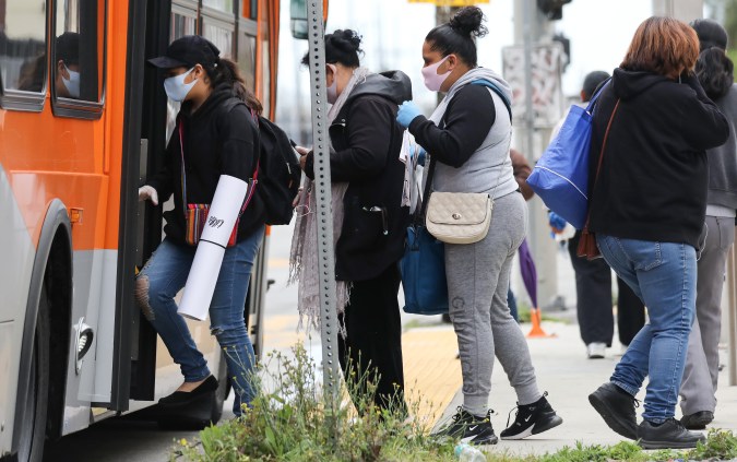 LOS ANGELES, CALIFORNIA - APRIL 06: People board a bus wearing face masks amid the coronavirus pandemic on April 6, 2020 in south Los Angeles, California. Nearly 11,000 people have died in the U.S. from COVID-19. (Photo by Mario Tama/Getty Images)