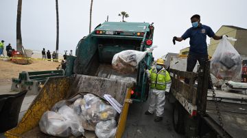 Sanitation workers remove trash near homeless encampments at the Venice Beach Boardwalk ahead of the Independence Day holiday weekend, July 2, 2021 in Los Angeles, California. - Authorities are offering unhoused people lining near the beach a path to permanent housing in an effort to clear the popular tourist destination of homeless camps before the July 4th holiday weekend. The number of homeless encampments along the popular tourist destination exploded during the coronavirus pandemic, making it a political flashpoint. (Photo by Robyn Beck / AFP) (Photo by ROBYN BECK/AFP via Getty Images)