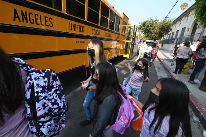 Students and parents arrive masked for the first day of the school year at Grant Elementary School in Los Angeles, California, August 16, 2021. - To stem the spread of Covid-19 coronavirus teachers in Los Angeles are required to be fully vaccinated against Covid-19 by October 15 and both teachers and students are required to wear masks inside school buildings. Issues wih the new "Daily Pass" health check app caused confusion and long lines on the first day back to school. (Photo by Robyn Beck / AFP) (Photo by ROBYN BECK/AFP via Getty Images)
