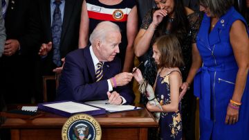 Biden le entregó un bolígrafo a Brielle Robinson, la hija del sargento de primera clase Heath Robinson, después de firmar la Ley PACT el 10 de agosto de 2022.