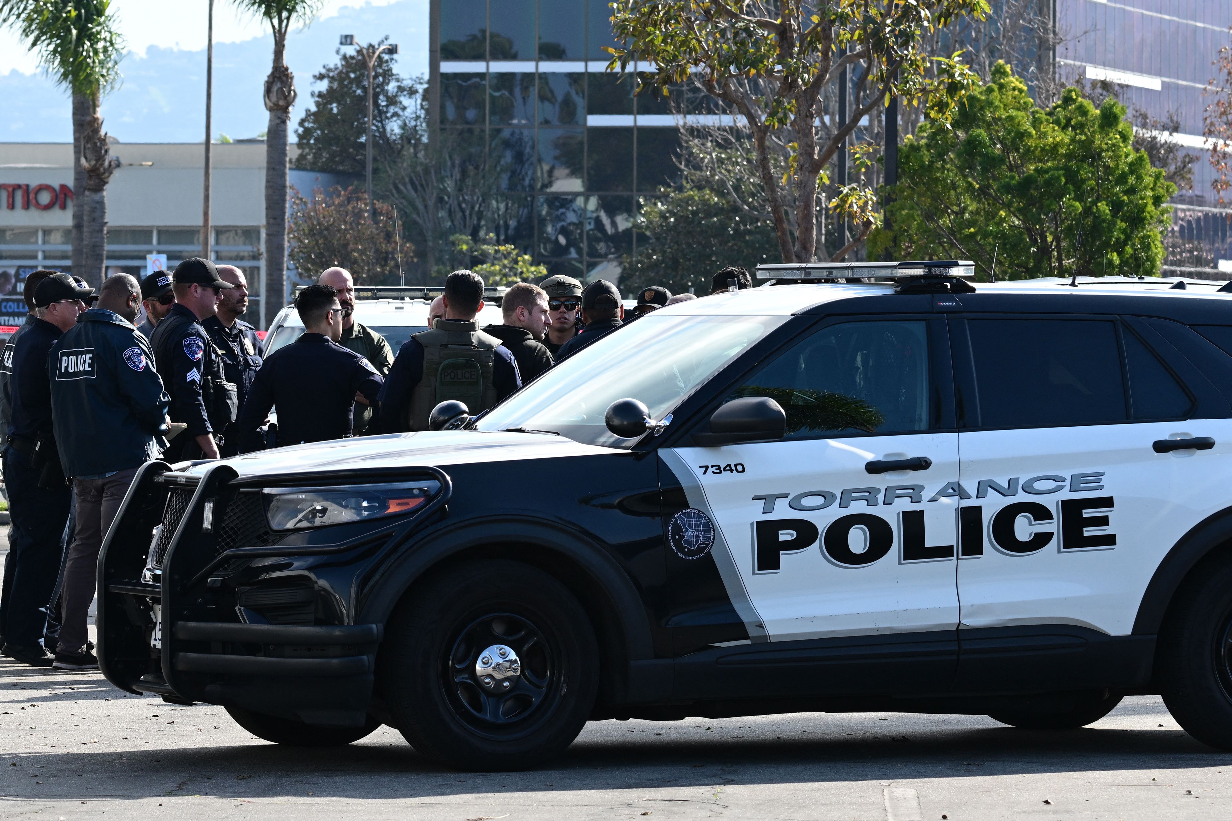 Torrance police officers and other law enforcement gather after breaking into a van with a body in the driver's seat in Torrance, California, on January 22, 2023. - California police hunting the gunman who killed 10 people at a dance club during Lunar New Year celebrations broke into a van after a lengthy standoff Sunday, where images showed a body slumped in the driver's seat. The hunt began 12 hours earlier after a man -- described by police as Asian -- began firing at a club in Monterey Park, a city in Los Angeles County with a large Asian community. (Photo by Robyn BECK / AFP) (Photo by ROBYN BECK/AFP via Getty Images)