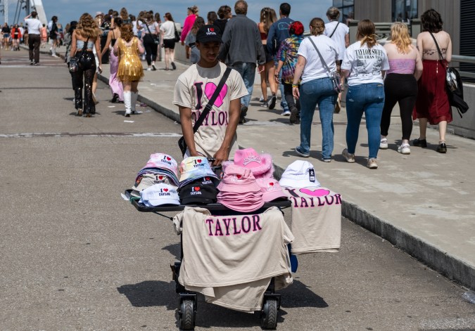 NASHVILLE, TN - MAY 06: A young man sells t-shirts and hats as Fans make their way to Nissan Stadium ahead of artist Taylor Swift's second night of performance on May 6, 2023 in Nashville, Tennessee. Thousands of fans traveled from across the country for Swift's three night stop in Nashville as her "Eras" tour continues. Fans attending the concert dressed according to their favorite Taylor Swift eras before the three hour show, featuring 44 of Swift's songs from her last 10 albums. (Photo by Seth Herald/Getty Images)