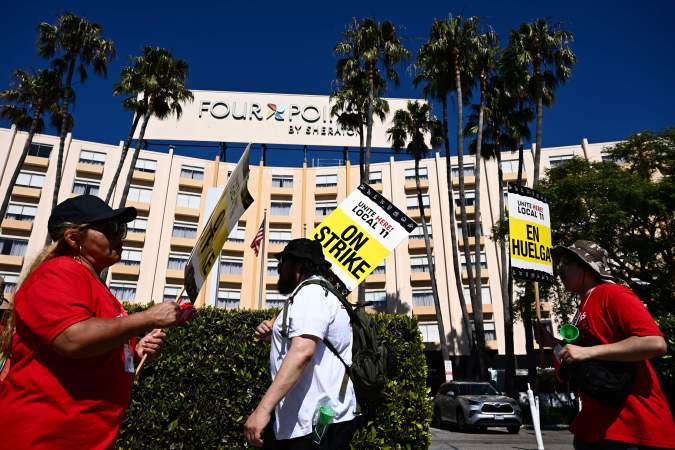 People hold on strike picket signs in support of striking hotel workers with United Here Local 11 outside of the Four Points by Sheraton hotel at Los Angeles International Airport (LAX) in Los Angeles, California on July 11, 2023. Thousands of hotel workers in Southern California walked off the job in an effort to secure higher pay and improvements in health care and retirement benefits amidst rising inflation and housing costs. (Photo by Patrick T. Fallon / AFP) (Photo by PATRICK T. FALLON/AFP via Getty Images)