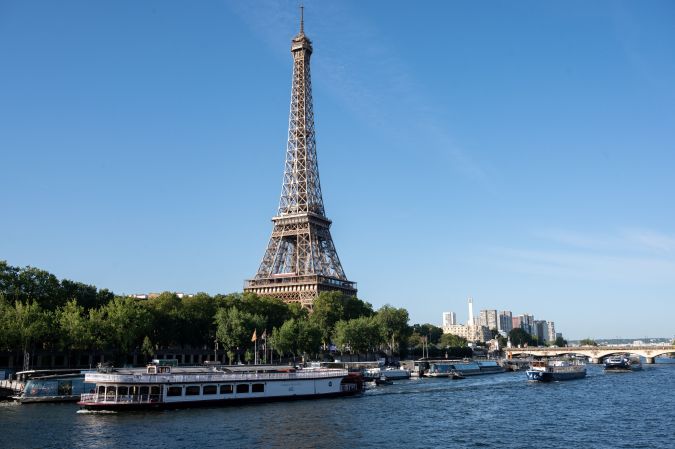 A peniche boat sails past the Eiffel Tower on the River Seine on July 17, 2023, during a parade to test "maneuvers", "distances", "duration" and "video capture" of the future opening ceremony of the Paris Olympics in 2024. For this mini-rehearsal, the total fleet is made up of 57 boats, 39 representing the delegations - slightly less than half as many as for the actual ceremony in 2024 - and 18 others providing support (assistance, first aid) as well as Olympic Broadcasting Services (OBS), the Olympic TV broadcaster. (Photo by BERTRAND GUAY / AFP) (Photo by BERTRAND GUAY/AFP via Getty Images)