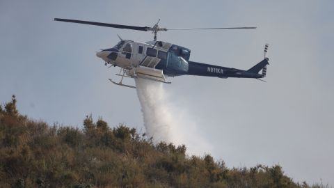 Water is dropped as the Agua Fire burns in Soledad Canyon, near Agua Dulce, California, July 25, 2023. A heat wave in excess of 90 degrees Farenheit (32 Celsius) makes emergency response both difficult and dangerous. (Photo by DAVID SWANSON / AFP) (Photo by DAVID SWANSON/AFP via Getty Images)
